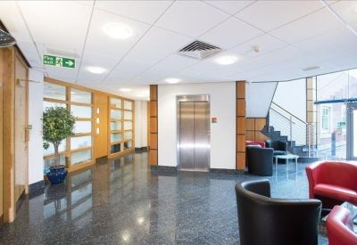Lift lobby and lounge area featuring red armchairs and polished stone floors.