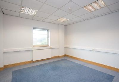 Empty private office with blue carpeting and natural light from a central window.