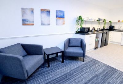Communal breakout area featuring blue armchairs and abstract wall art.