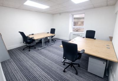 Four-person office suite with light wood desks and grey carpet.