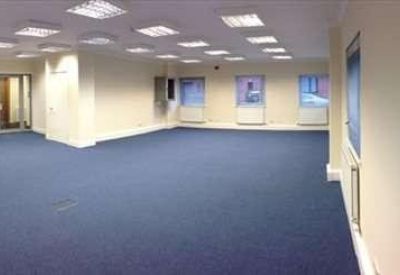 Spacious open-plan office with blue carpeting and bright recessed ceiling lights.