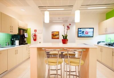 Kitchen and breakout area with a central island, bar stools, and lime green splashback.