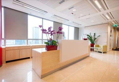 Modern reception desk with blonde wood finishes and purple orchid arrangements.