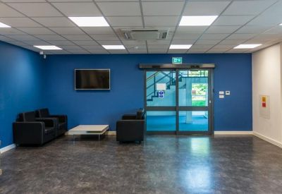 Spacious reception area with blue feature wall, black sofas, and television.