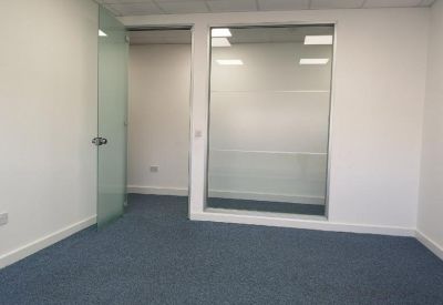 Bright office space with blue carpet and a frosted glass wall partition.
