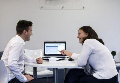 Informal meeting space with two people discussing work around a laptop.