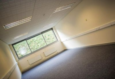 Bright, empty carpeted office suite with large windows and white walls.