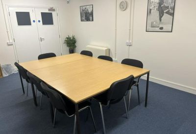 Meeting room with a central wooden table and black chairs on blue carpet.