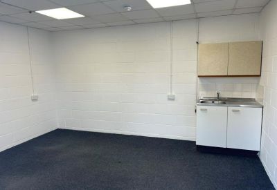 Small office kitchenette with white cabinets and a stainless steel sink.