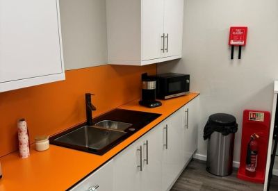 Vibrant communal kitchen area featuring bright orange countertops and splashback.