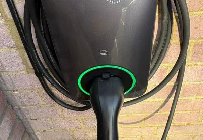 Wall-mounted Project EV electric vehicle charging station on a brick wall.
