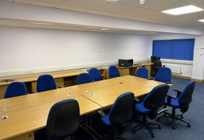 A secondary meeting room featuring a long wooden table and blue upholstered chairs.