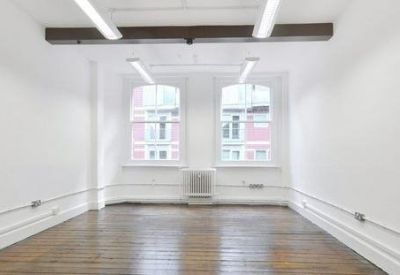 Bright open-plan office with white walls and exposed ceiling beam.