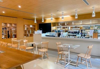 Modern office café and kitchen area with light wood cabinetry and high-top seating.