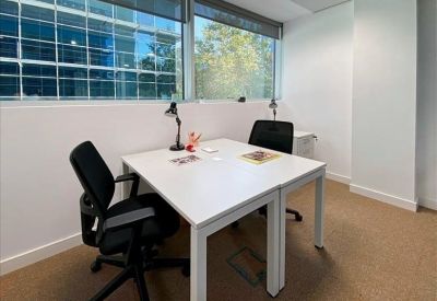 Private two-person office suite with white desks and large windows.