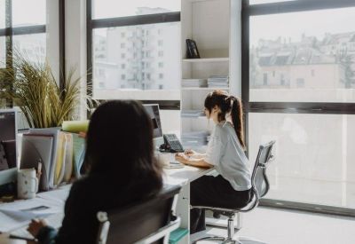 Bright shared office with wooden desks and large windows overlooking the city.