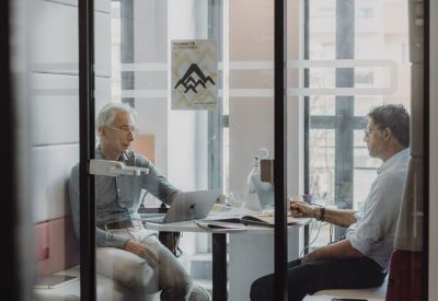Modern two-person meeting pod with glass doors and a central table.