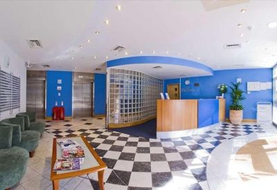 Modern building reception with blue walls, checkered flooring, and a curved wooden front desk.