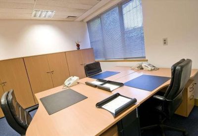 Private three-person office suite with light wood desks and black leather chairs.