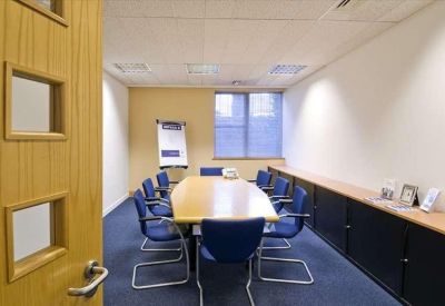 Professional meeting room with a long wooden table, blue chairs, and a whiteboard.
