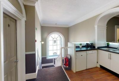 Clean communal kitchen area with white cabinetry and a window view.