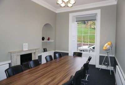 Elegant meeting room with a wooden table, fireplace, and natural light.
