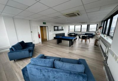Spacious communal breakout area with blue velvet sofas, a pool table, and large windows.