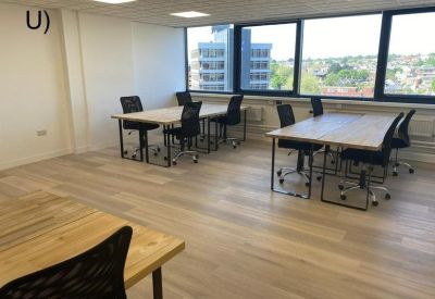 Private office space with wooden desks and black ergonomic chairs near large windows.