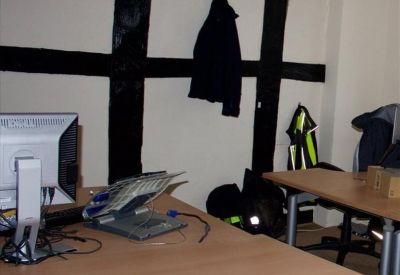 Workspace featuring historic black timber framing on white walls and wooden desks.