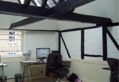 Bright attic office space with exposed dark wooden beams and a large skylight.