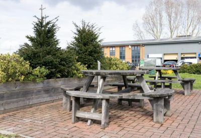 Outdoor patio area with heavy timber picnic tables and a low wooden retaining wall.