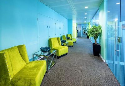 Long corridor lounge with bright blue walls, lime green velvet armchairs, and a glass coffee table.