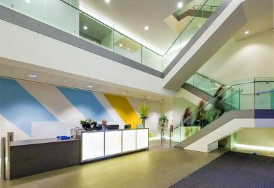 Spacious modern reception area with light-up front desk, colorful wall graphics, and glass-railed stairs.