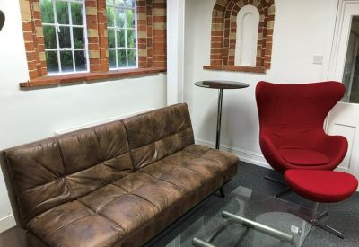 Breakout area featuring a brown leather sofa and a red designer egg chair.