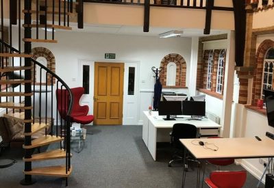 Open-plan workspace in a converted chapel with vaulted ceilings and a spiral staircase.