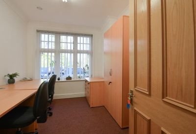 Private office suite with two desks, light wood cabinetry, and large windows.