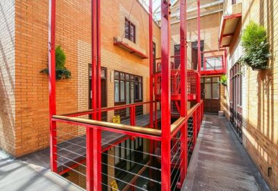Communal walkway with a striking red industrial staircase and brick walls.