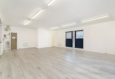 Bright open-plan office space with wood-style flooring and strip lighting.