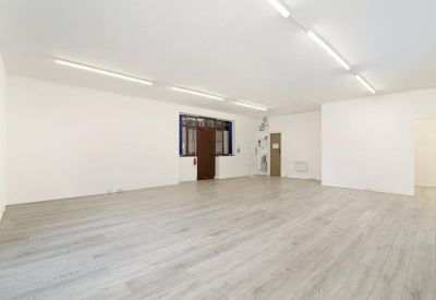 Spacious white-walled office room with a dark-framed glass partition door.