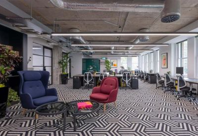 Open-plan office with patterned carpets, ergonomic chairs, and a comfortable lounge area.