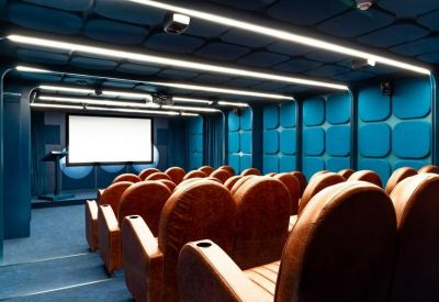 Private cinema or presentation room with plush tiered seating and blue textured walls.