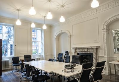 Spacious boardroom featuring a grand fireplace, large windows, and decorative ceiling cornicing.