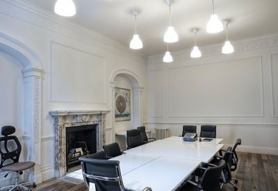 Elegant meeting room with a large white table, ornate marble fireplace, and multiple pendant lights.