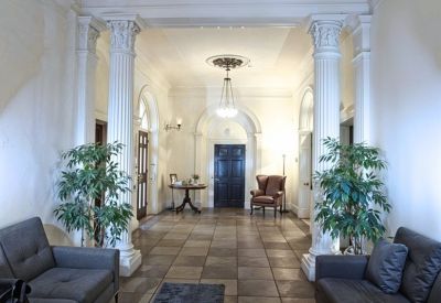 Grand reception lobby with white marble columns, tiled floors, and decorative chandelier.