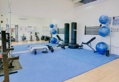 Spacious gym area with blue exercise mats, punching bags, and fitness balls.