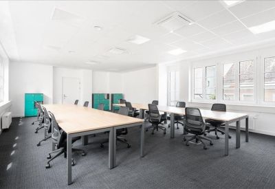 Spacious open-plan workspace with multiple desks and teal storage units.