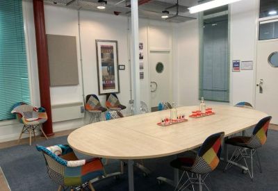 Meeting room with a round wooden table and colorful patchwork chairs.