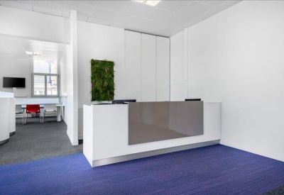 Bright reception area featuring a white and grey front desk and a vibrant green moss wall.