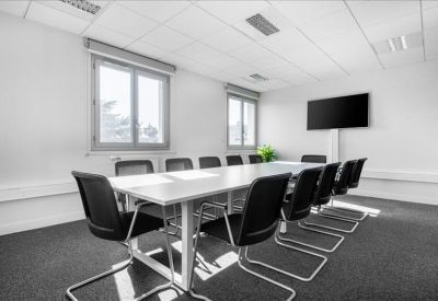 Spacious boardroom with a long white table, black chairs, and large windows.