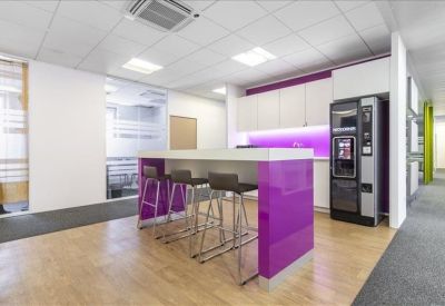 Modern breakroom area with a high table, purple base, and a coffee vending machine.